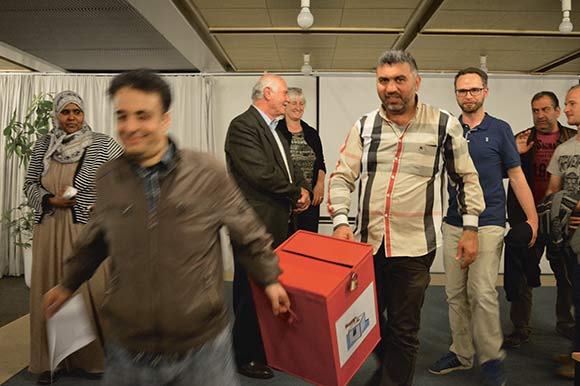Stemmeboksen blev fyldt med næsten 1500 stemmer – en tung opgave for stemmeudvalget. Her bæres boksen af Nezar Ajjawi (tv.) og Youssef Abdul Kader.