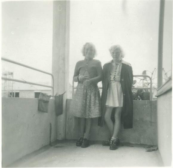 Aase og hendes søster på altanen, bagved skimtes byggestilladser